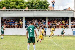 Torcedor rubro-negro do Vitória com expressão tensa assistindo ao jogo fora de casa, camisa vermelha e preta em destaque
