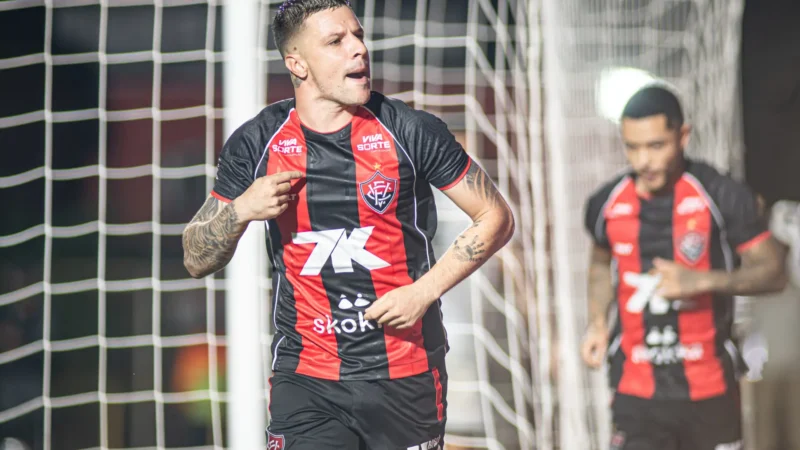 Renato Kayzer comemora com o punho erguido após marcar o gol da classificação do Vitória no Barradão lotado, com jogadores rubro-negros ao redor em euforia